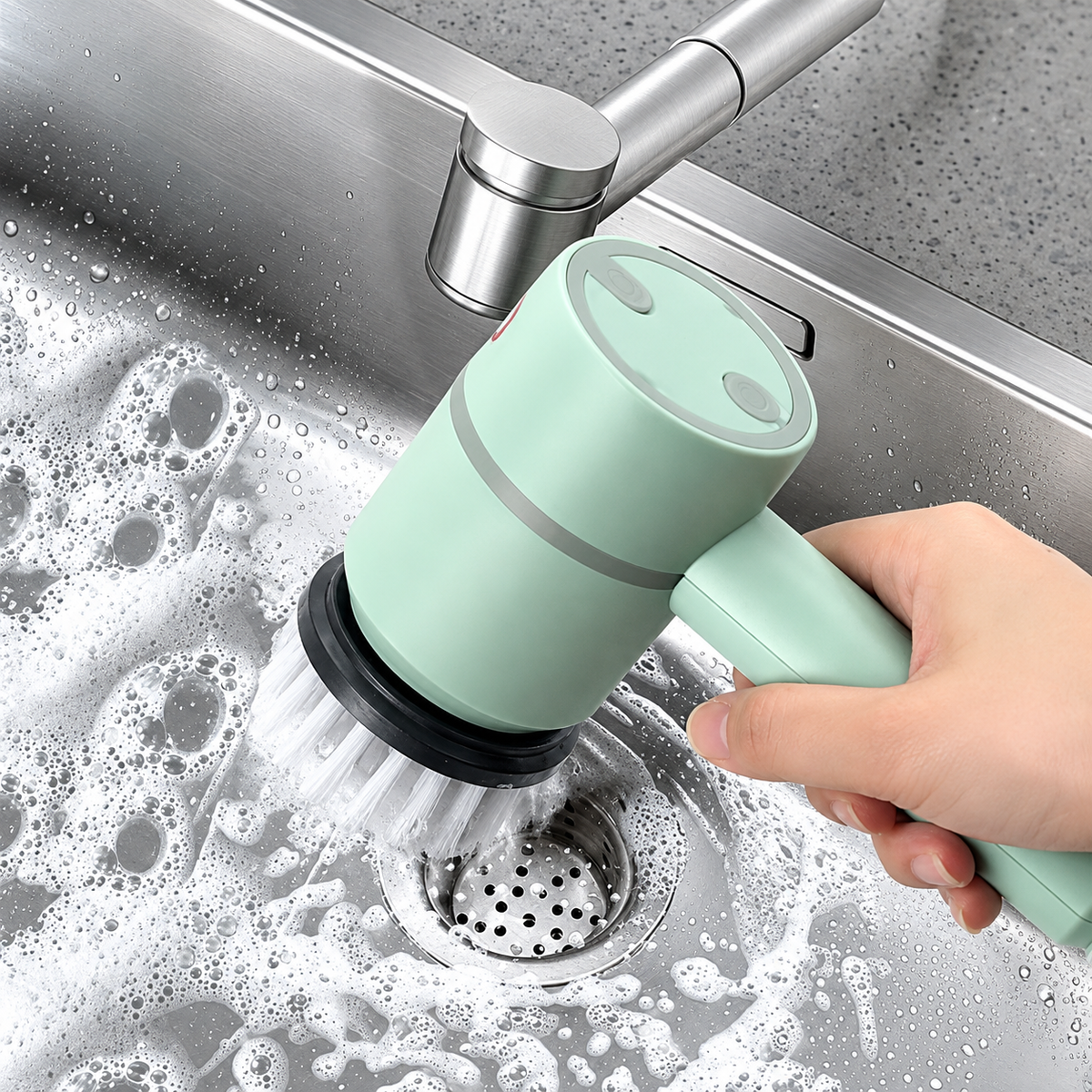 Cordless electric dish brush held in one hand above a washing-up bowl